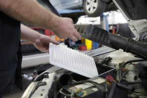 A mechanic tuning up a vehicle by clearing out the air filter
