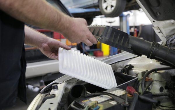 A mechanic tuning up a vehicle by clearing out the air filter