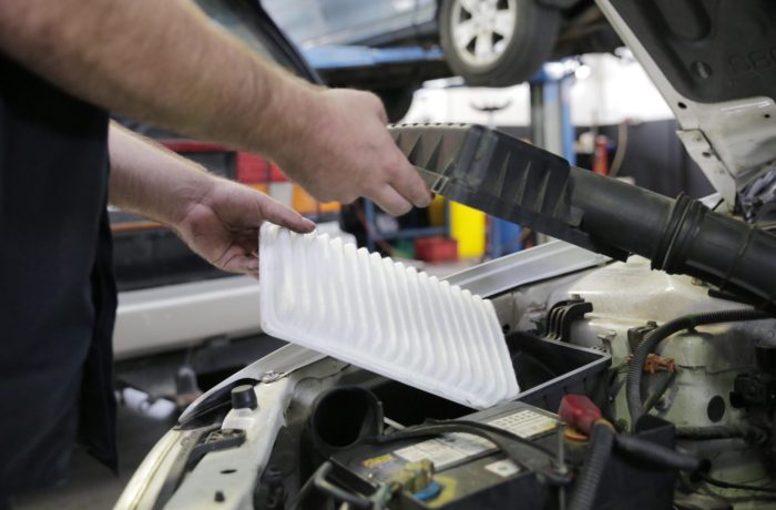 A mechanic tuning up a vehicle by clearing out the air filter