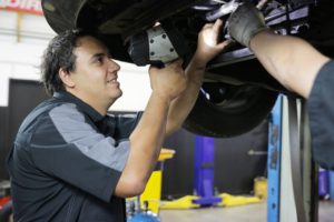 An Autoland mechanic underneath a car, conducting a WOF inspection.