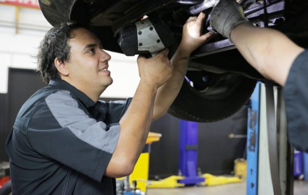 An Autoland mechanic underneath a car, conducting a WOF inspection.