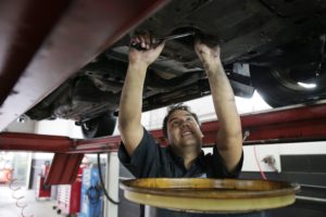 A mechanic clearing out a vehicle’s oil mid-service