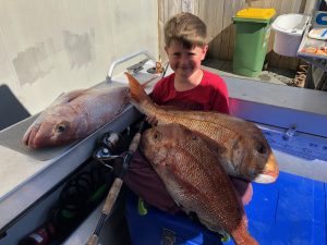Little kid Mason holding two large snapper fish