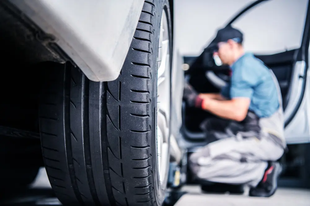 Car tyre in the foreground with a mechanic working beside the open driver’s door